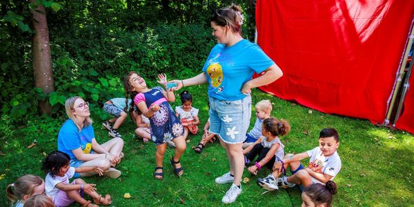 kinderen en 2 begeleiders zitten in een kring tijdens een activiteit van Speelkasteel
